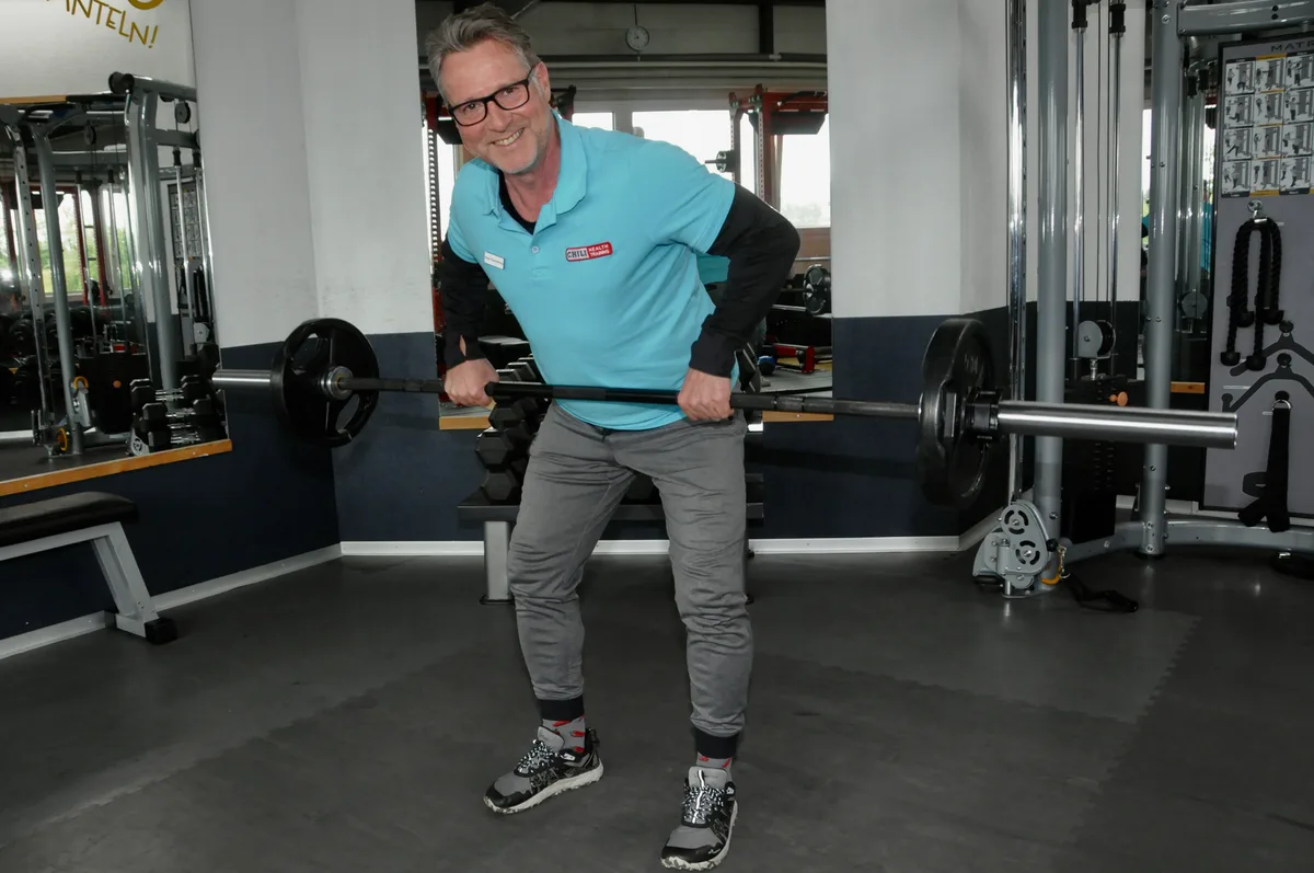 Ein Trainer mit der Langhantel.